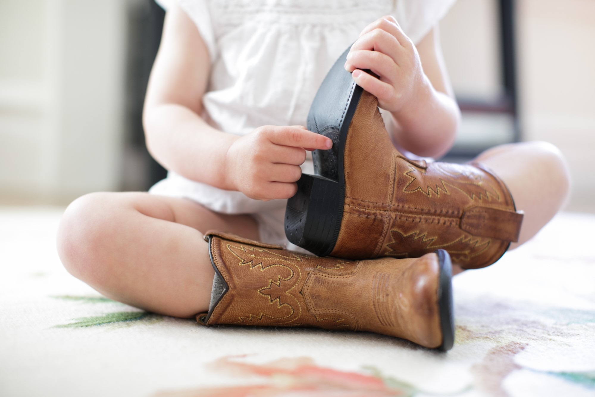 Neck down view of female toddler sitting on floor wearing cowboy boots Babymoon, poslední dovolenou před porodem, si užijte sama i ve dvou.